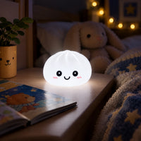 Veilleuse Dumpling blanche allumée sur une table de nuit