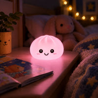 Veilleuse Dumpling rose allumée sur une table de nuit